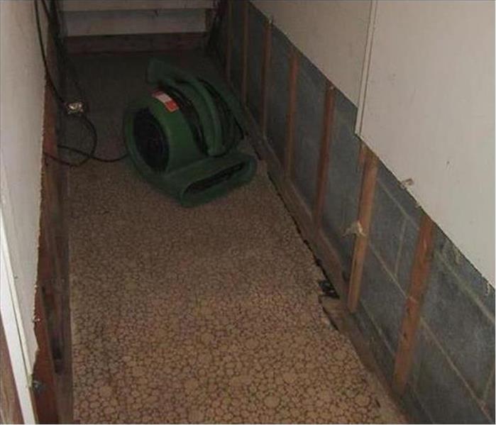 air mover under stairwell drying, removed walls show cinderblocks