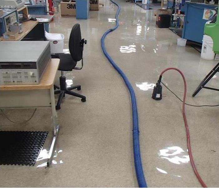 water on office floor, blue extraction hose and a small electric pump