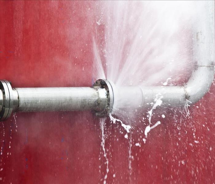 A burst water pipe with a red wall