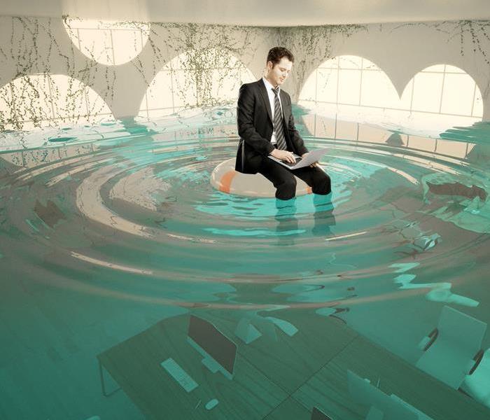 A man sitting on a float floating in water above desks